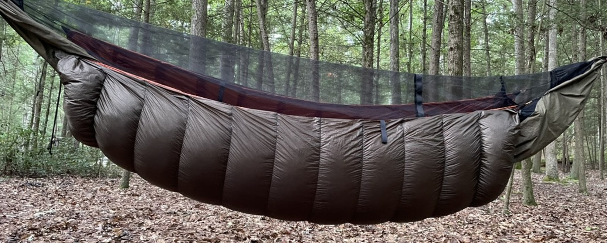 Jacks R Better brown down hammock underquilt hanging beneath a hammock in an autumn forest