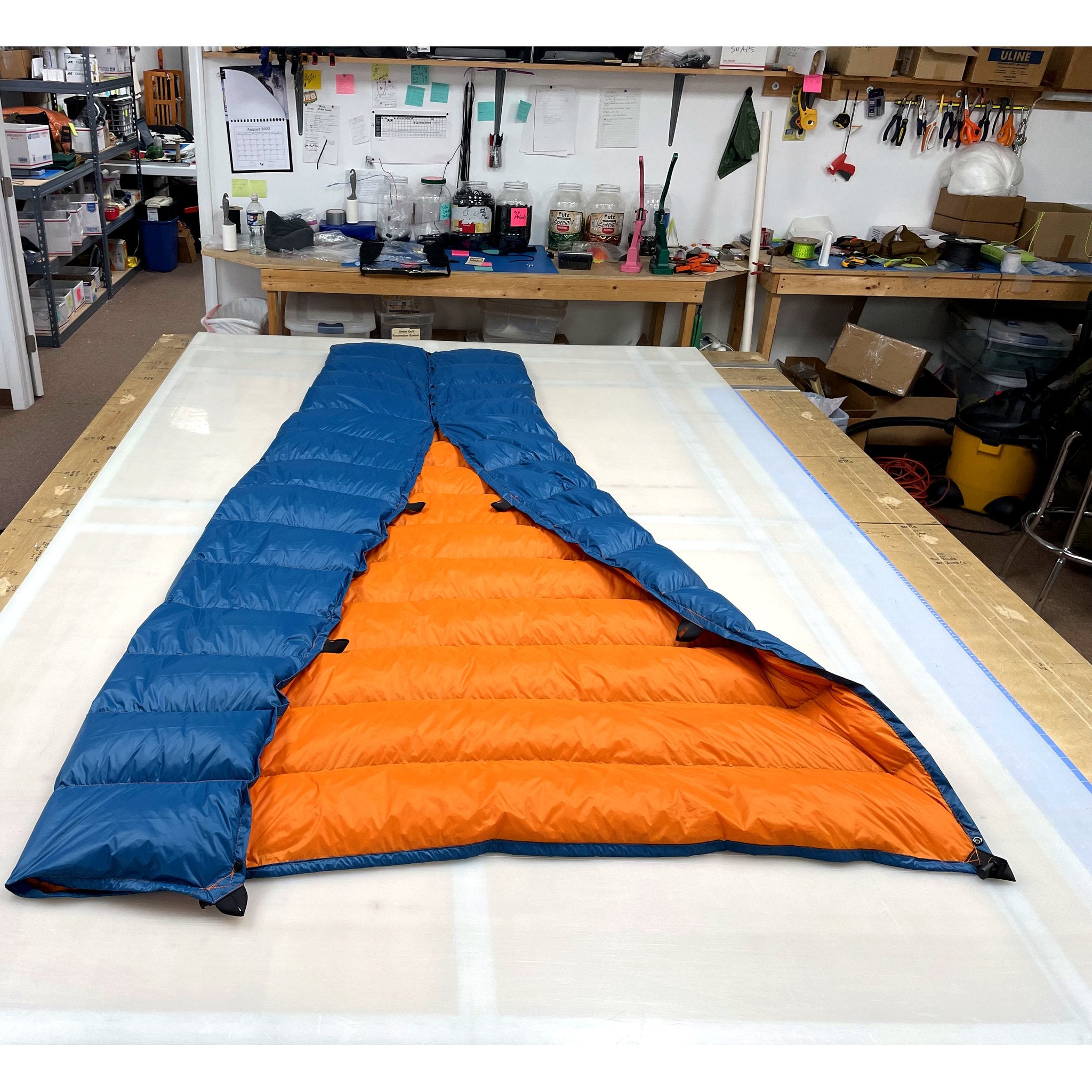 Custom ultralight backpacking quilt with a Brilliant Blue shell and Burnt Orange lining, opened to show the two-tone interior