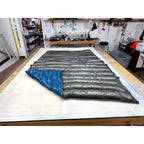 Custom ultralight backpacking quilt with a Charcoal Grey shell and Brilliant Blue lining shown at the folded corner