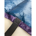 Close-up of a custom quilt's blue shell, purple edge binding, webbing strap, and contrast stitching