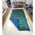 Custom ultralight backpacking quilt with a Forest Green shell and Moroccan Blue lining, folded to show both colors