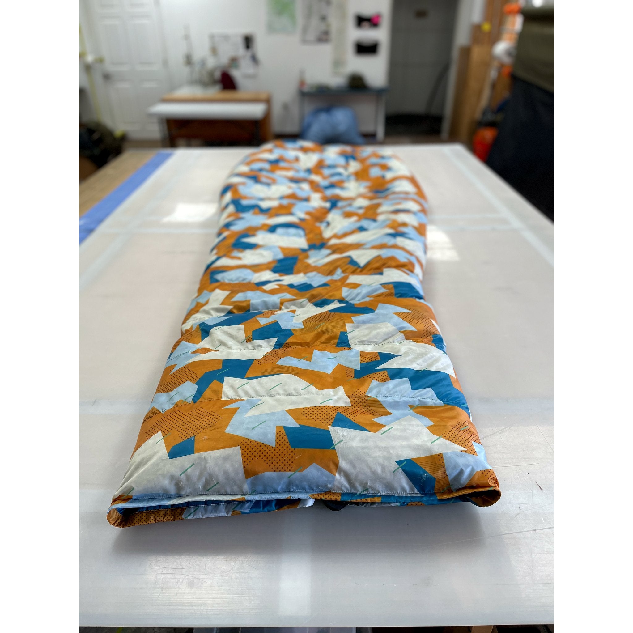 Custom ultralight backpacking quilt in the Geometric Camo Creamsicle print, an orange, blue, and cream pattern