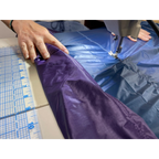 Hands guiding a purple and blue custom quilt through a sewing machine in the Jacks R Better Pennsylvania workshop