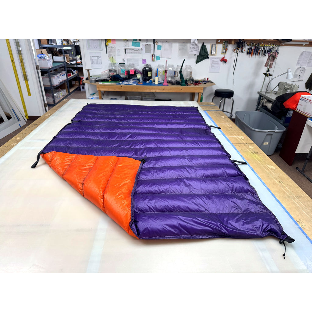 Custom ultralight backpacking quilt with a Purple shell and Burnt Orange lining, foot corner folded open