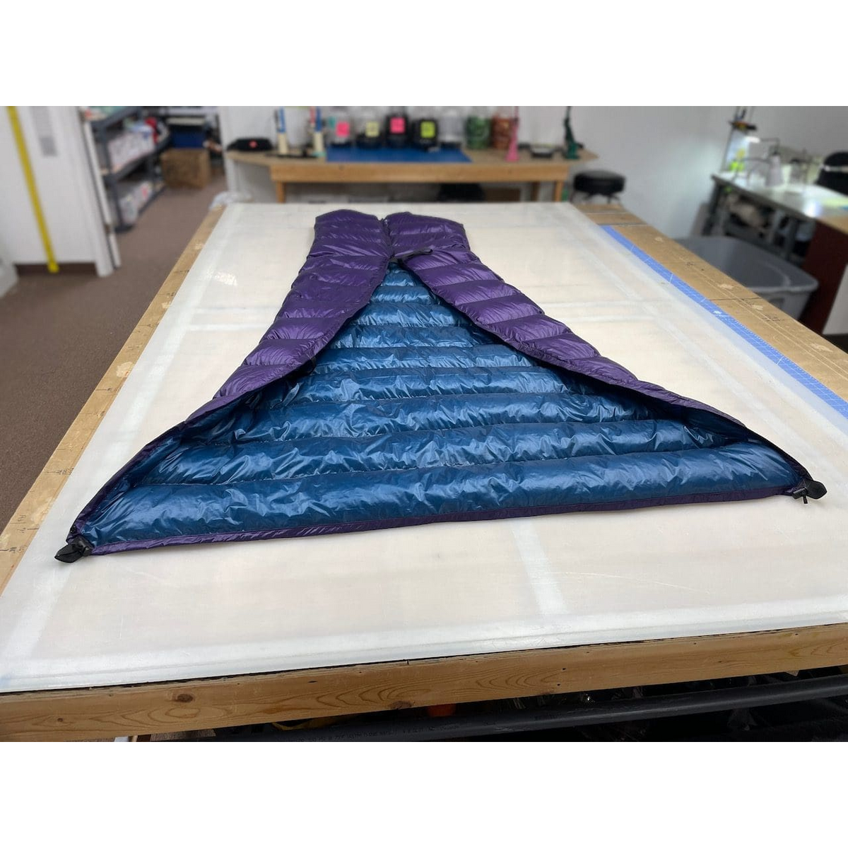 Custom ultralight backpacking quilt in Purple and Moroccan Blue, opened flat to show the two-tone interior