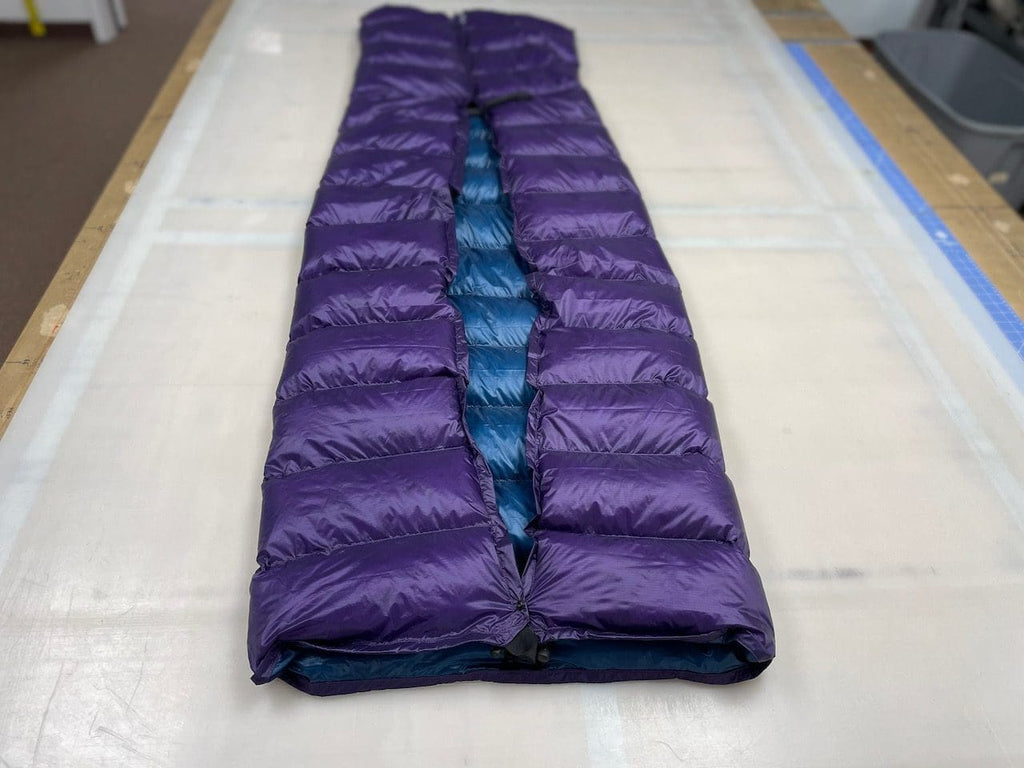 Custom ultralight backpacking quilt with a Purple shell and Moroccan Blue lining, formed into a foot box and laid full length on the workshop table