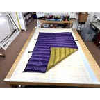 Custom ultralight backpacking quilt with a Purple shell and Moss Green lining, folded to show both colors