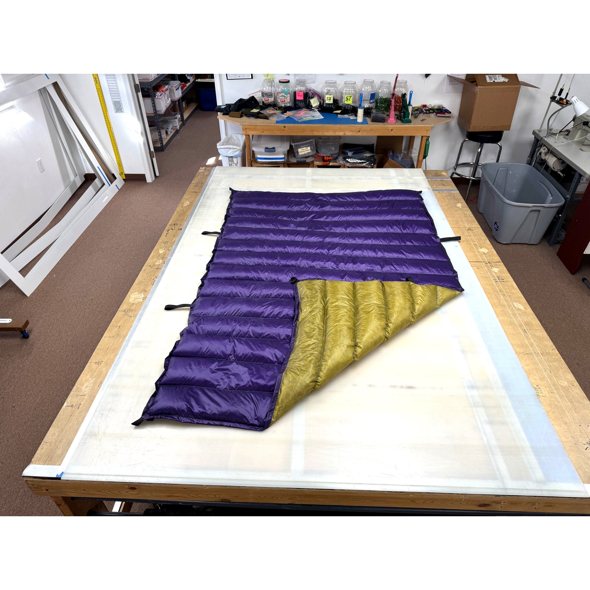 Custom ultralight backpacking quilt with a Purple shell and Moss Green lining, folded to show both colors