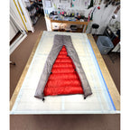 Custom ultralight backpacking quilt with a Titanium Grey shell and Brick Red lining, opened to show the interior