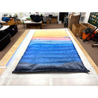 Custom ultralight backpacking quilt in the Wayah Bald Sunset print, a gradient fading from orange to deep blue