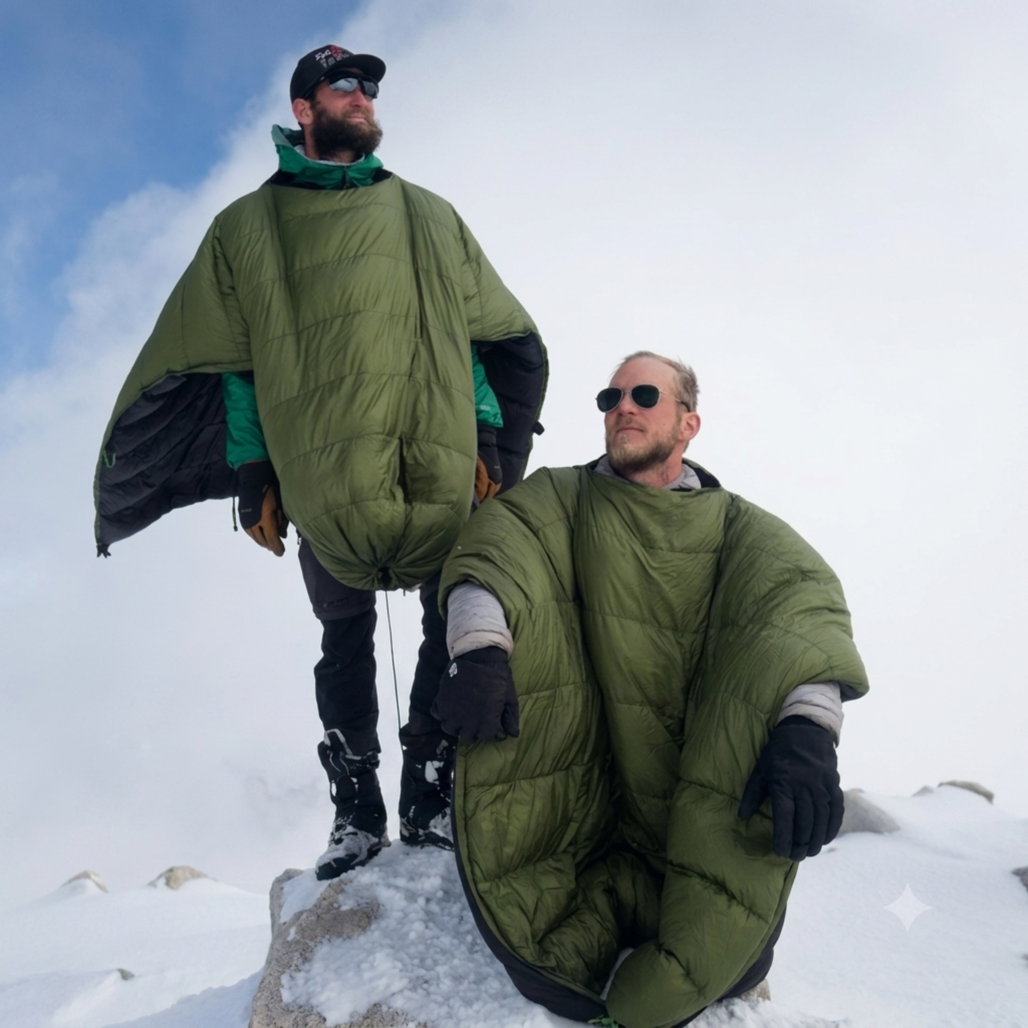 Two campers wearing the High Sierra Sniveller 0° down quilt on a snowy mountain summit
