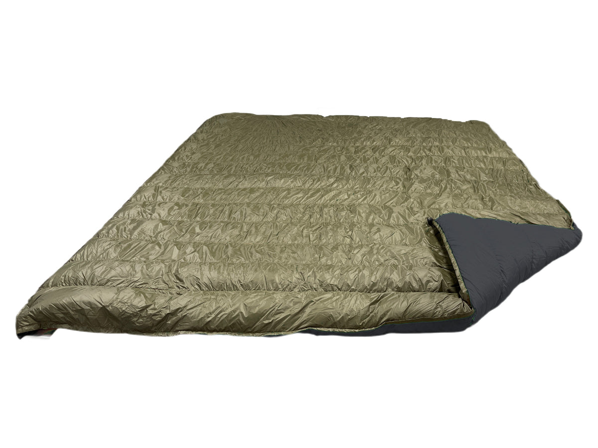 Jacks R Better Overland 20°F overlanding and RV camping quilt laid flat, dark olive shell with the corner turned back to show the black lining