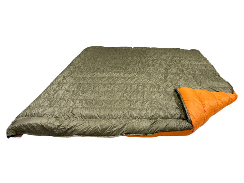 Jacks R Better Overland 20°F overlanding and RV camping quilt laid flat, dark olive shell with the corner turned back to show the burnt orange lining